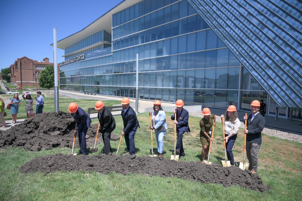 people shoveling dirt at the groundbreaking event